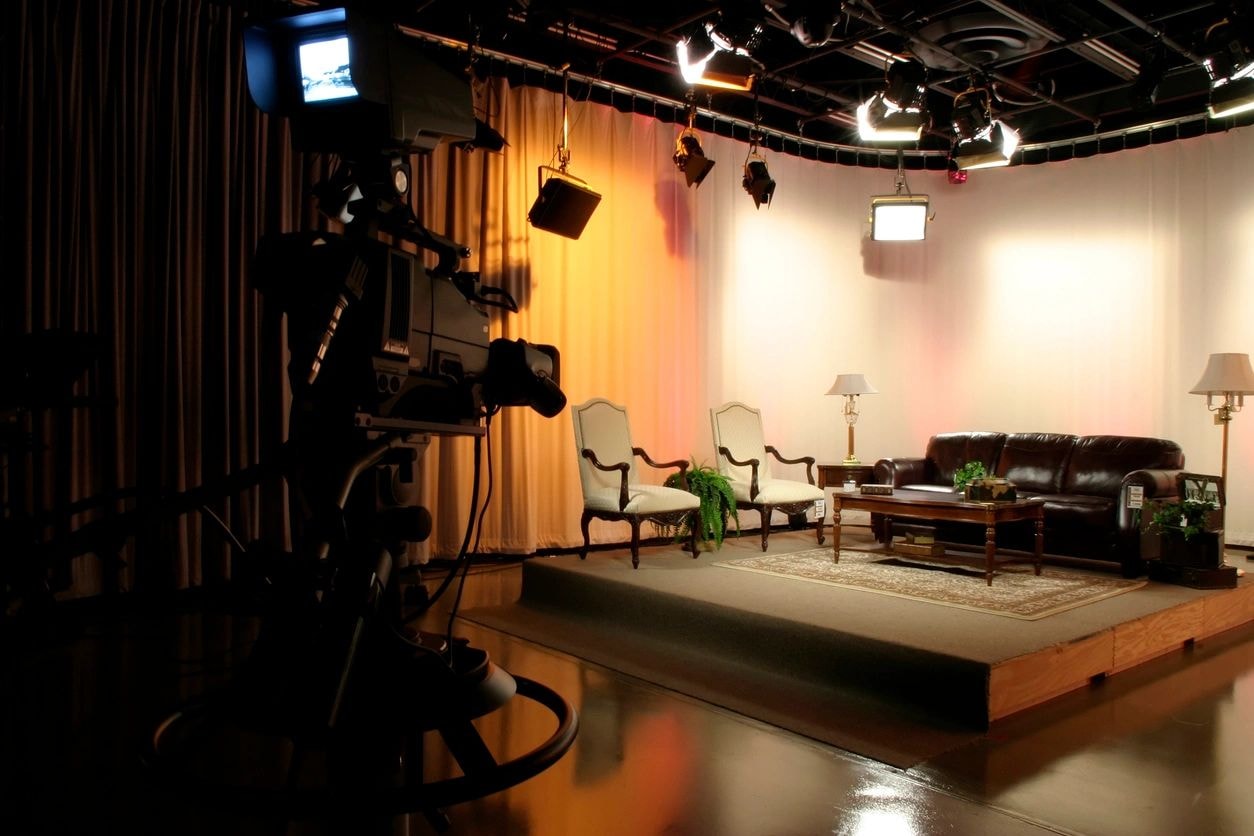 Television studio set with two armchairs, a sofa and warm stage lighting